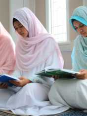 A group of young Muslim girls wearing hijabs, sitting together and reading the Holy Quran