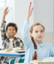 Group of cheerful schoolchildren sitting at their desks in a classroom