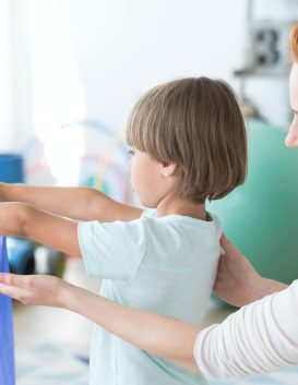 A physiotherapist gently supporting a young child
